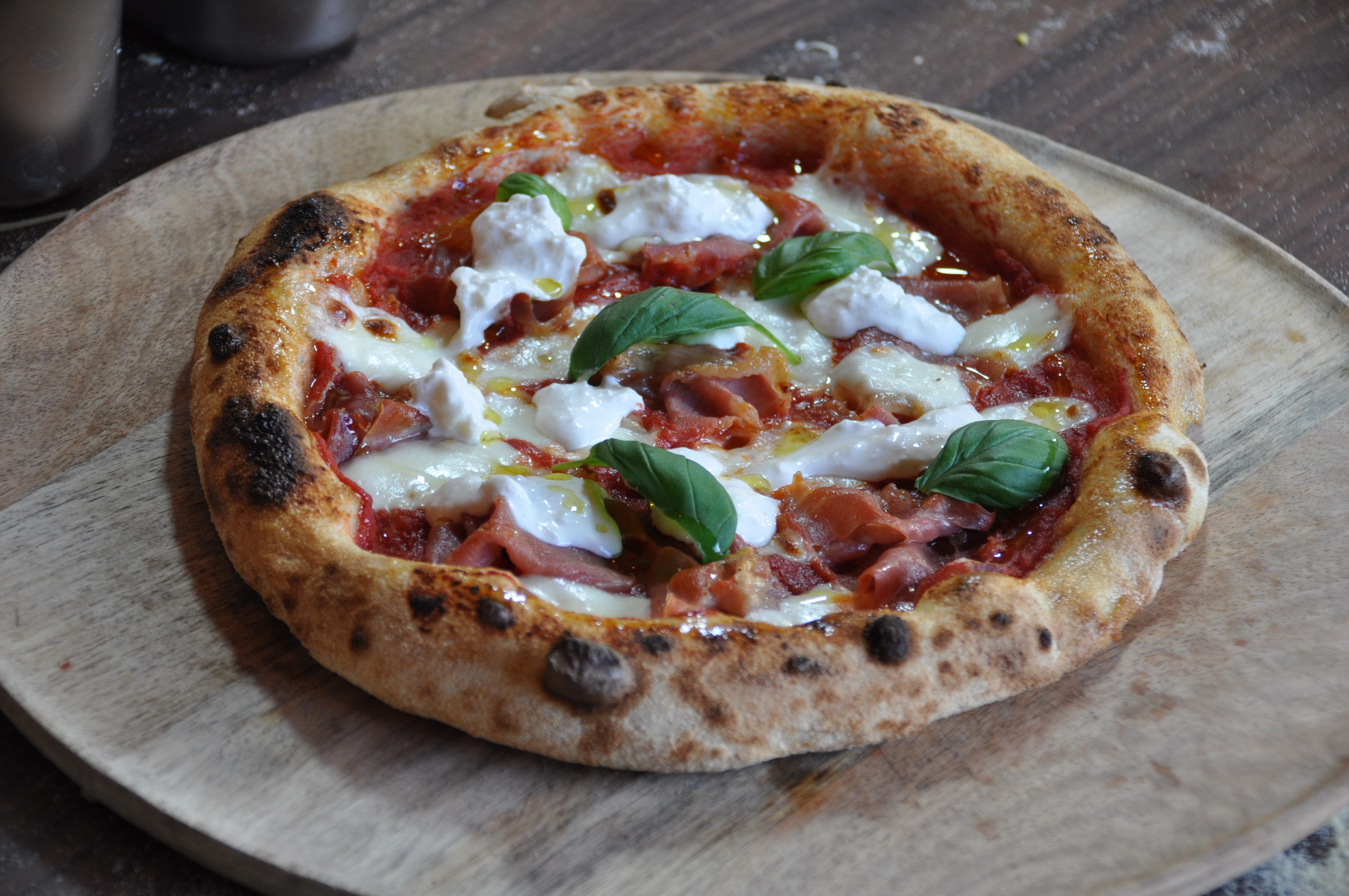Burrata pizza met prosciutto en basilicum