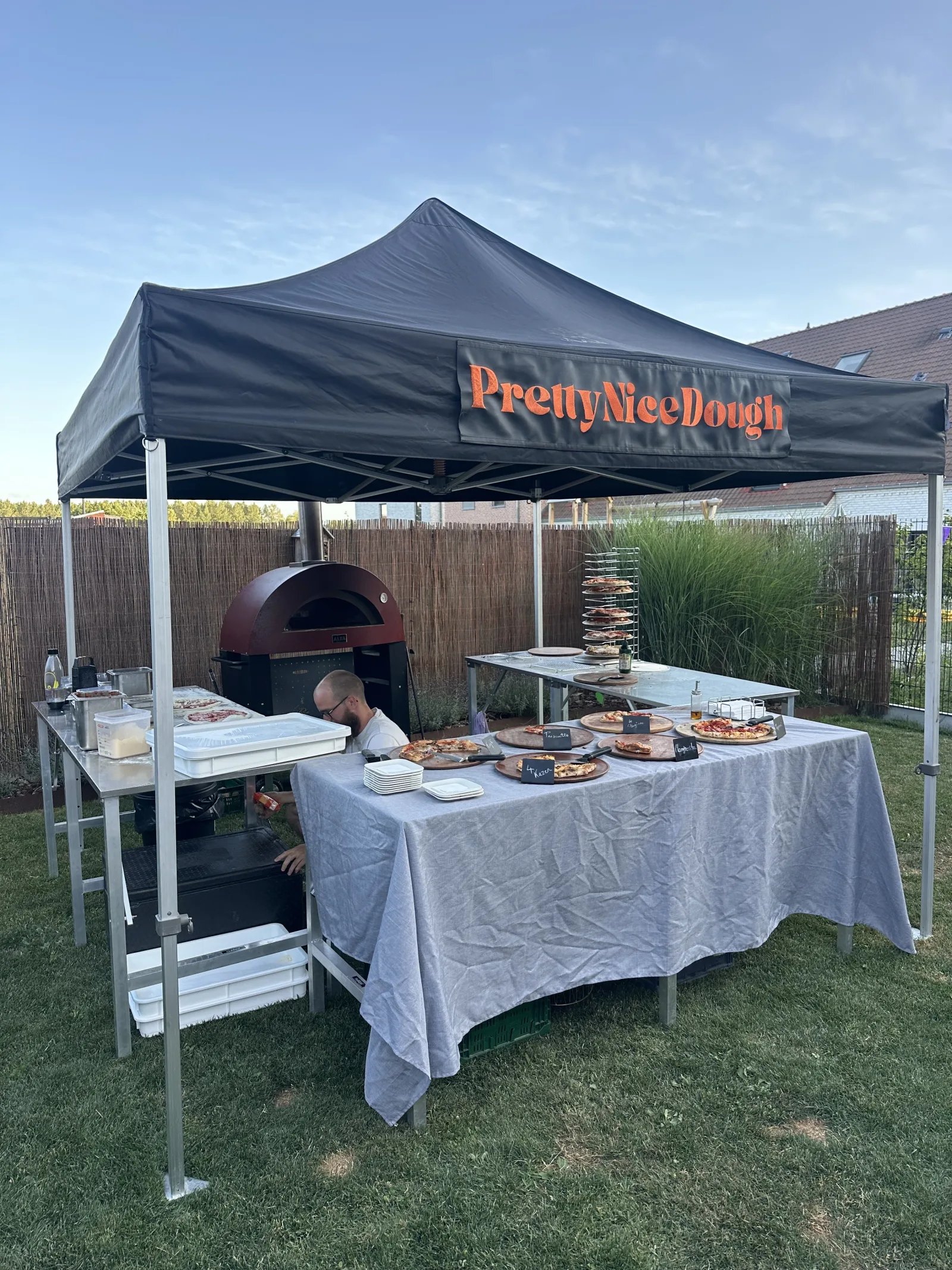 De volledige Pretty Nice Dough set-up: een tent met tafels en de houtoven eronder, geen foodtruck